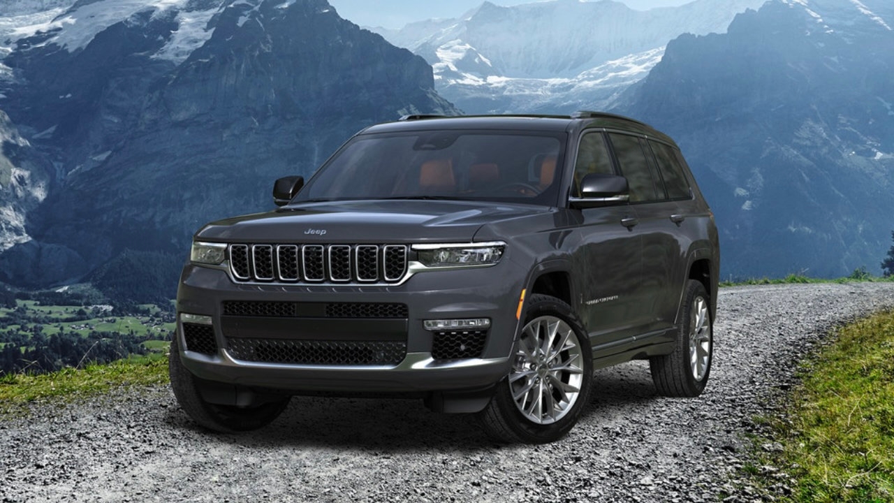 Un Jeep Grand Cherokee stationné sur un chemin de gravel avec un arrière plan de montagne.