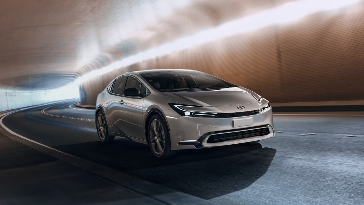 Silver Toyota Prius 2025 driving in a lit tunnel, featuring a futuristic and aerodynamic design enhanced by the light reflections.