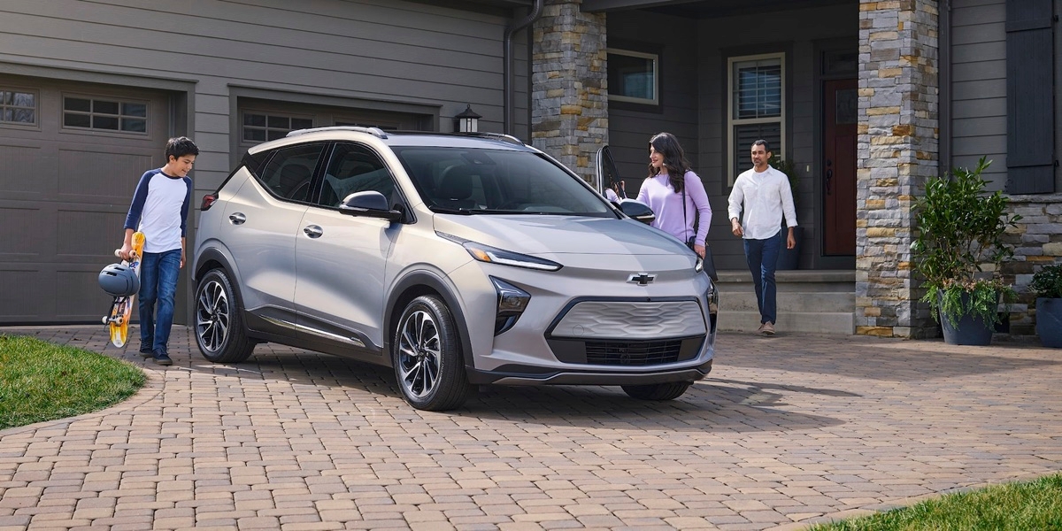 Une famille s'apprête a monter à bord du Chevrolet Bolt EUV devant leur résidence.