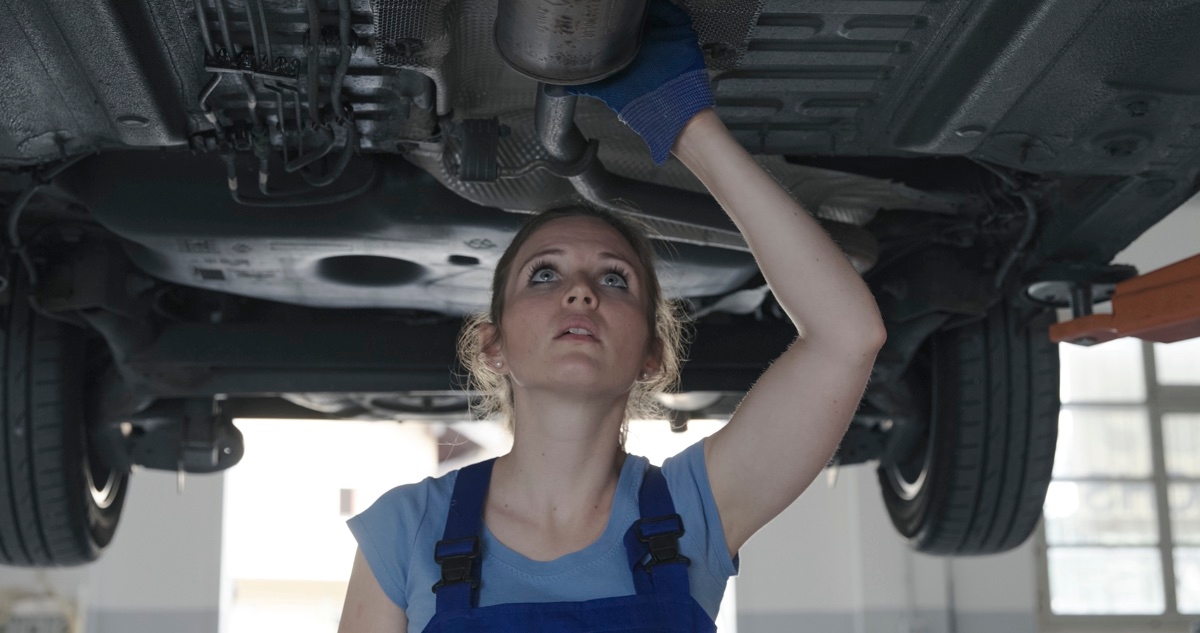 Une femme garagiste inspecte une voiture pour vérifier qu'il n'y a pas de rouille sous le véhicule.