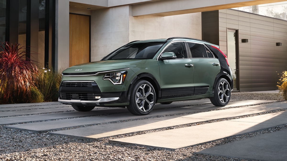 Kia Niro hybrid in forest green parked in front of a contemporary house, highlighting its urban and eco-friendly design.