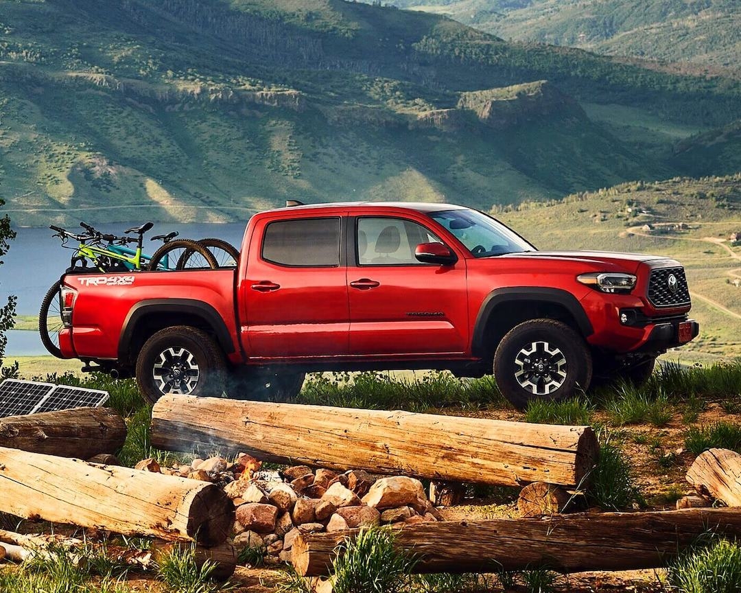 Red Toyota Tacoma TRD Sport with bikes, reliable pre-owned truck perfect for towing and adventure.